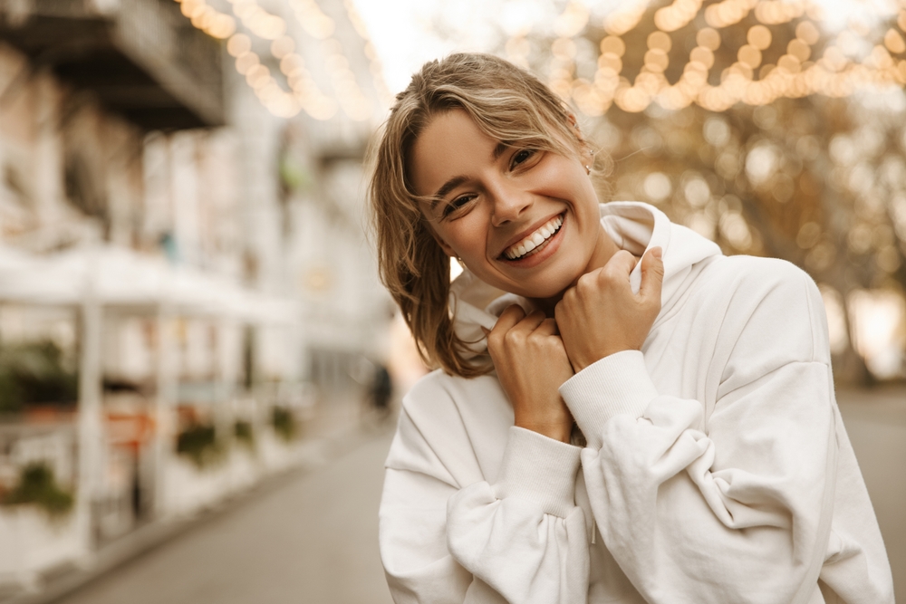 Bright Smile After Dental Bridges Treatment Happy young woman outdoors smiling confidently after receiving dental bridges, showcasing restored teeth and natural appearance