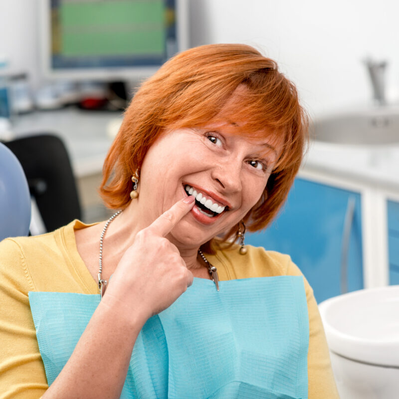 dental patient shows where her dental implant is placed