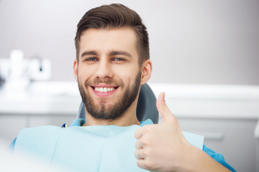 Relieved Patient After Dental Treatment - Experiencing an Emergency? Smiling male patient giving thumbs up after emergency dental care - Experiencing an Emergency?