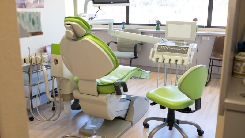 A dental treatment room with green and white dental chairs, equipment, and a large window - Newport Dental Bellevue WA A dental treatment room with green and white dental chairs, equipment, and a large window - Newport Dental Bellevue WA