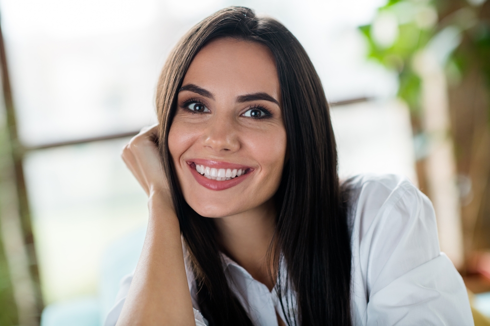 Bright Confident Smile Indoors - Dental Fillings Woman with long dark hair smiling confidently in a bright indoor setting - Dental Fillings