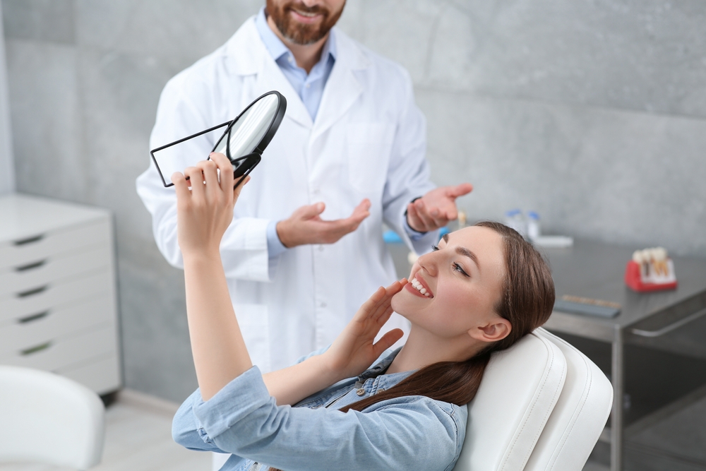 Patient Examining Dental Bridges Result Smiling woman looking in a mirror at her teeth during a dental consultation, highlighting successful dental bridges treatment - Bridges