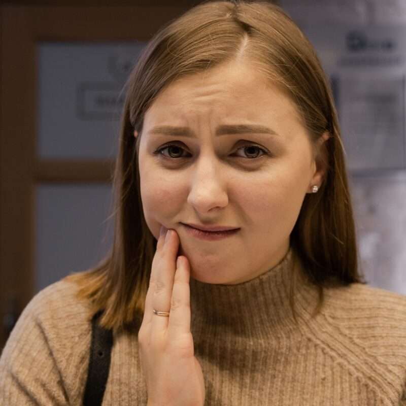 Woman wondering if her aching teeth counts as a dental emergency